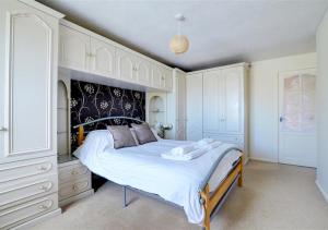 a bedroom with a large bed with white cabinets at Summer Breeze in Northam