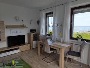 ein Wohnzimmer mit einem Esstisch und einem TV in der Unterkunft Ferienwohnung mit Meerblick in Dahme