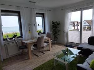 ein Wohnzimmer mit einem Tisch, Stühlen und Meerblick in der Unterkunft Ferienwohnung mit Meerblick in Dahme