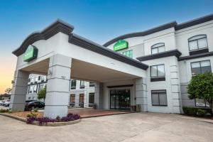 un grand bâtiment blanc avec un parking dans l'établissement Wingate by Wyndham Lafayette Airport, à Lafayette