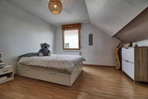 un osito de peluche sentado en una cama en un dormitorio en Maison Le Vignoble avec jardin - 6 personnes, en Ribeauvillé