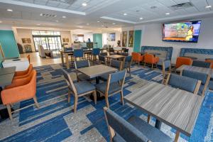 a dining room with tables and chairs and a flat screen tv at Wingate by Wyndham Lafayette Airport in Lafayette