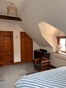 um quarto com uma cama, uma cadeira e uma janela em Converted Coach House Holt, Wiltshire em Holt
