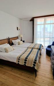 a bedroom with a large bed and a large window at Boutique Inn & Restaurant - Casa dos Suécos in Figueira da Foz