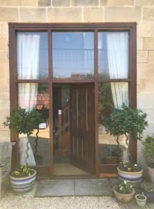 uma porta de vidro com dois vasos de plantas em frente em Converted Coach House Holt, Wiltshire em Holt