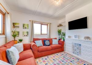 a living room with a red couch and a fireplace at Resthaven in Ilfracombe