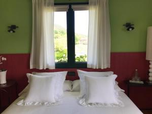 a bedroom with a bed with white pillows and a window at Basarte Cottage in Bakio