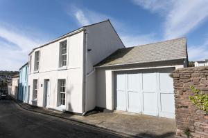 uma casa branca com uma garagem branca em Bay Cottage, Brixham em Brixham