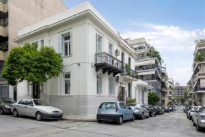 Biały budynek z samochodami zaparkowanymi przed nim w obiekcie Acropolis Villa w Atenach