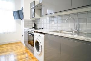 uma cozinha com uma máquina de lavar roupa e um lavatório em Centra Studios em Londres