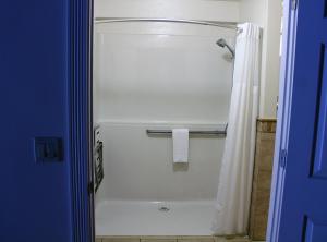 baño con ducha con cortina blanca en Silverton Inn & Suites en Silverton