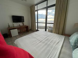 1 dormitorio con cama y ventana grande en Apartamento no tropical executive hotel com varanda, 1 cama de casal e 2 camas de solteiro en Manaos