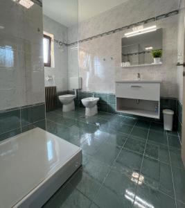 uma casa de banho com 2 WC, um lavatório e uma banheira em Magnolia Apartments em Izola