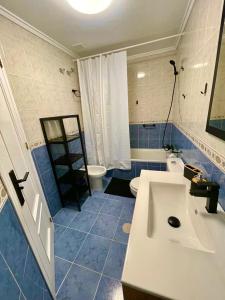 baño de azulejos azules con lavabo y aseo en Capitan Friday Apartments, en Torrevieja