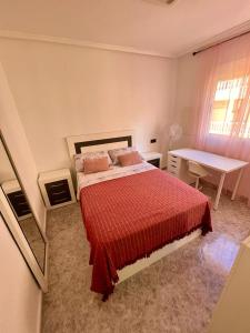 1 dormitorio con cama, mesa y escritorio en Capitan Friday Apartments, en Torrevieja