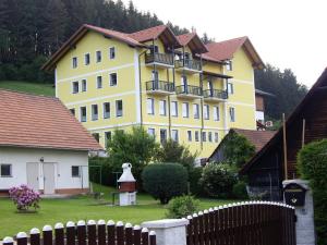 a large yellow building with a fence in a yard at Landgasthof Sepplwirt in Kindberg