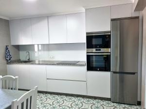 La cuisine est équipée de placards blancs et d'un réfrigérateur en acier inoxydable. dans l'établissement Casa Alcabre (Samil), à Vigo