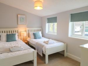 two beds in a room with two windows at Riverside Cottage in Norwich