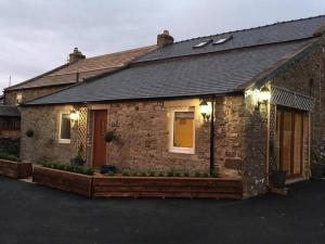 a brick house with a porch with lights on it at The Byre @ Cow Close - Stay, Rest and Play in the Dales. in Leyburn