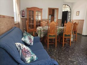 sala de estar con sofá azul, mesa y sillas en Villa Bendición - Subbética Cordobesa en Doña Mencía