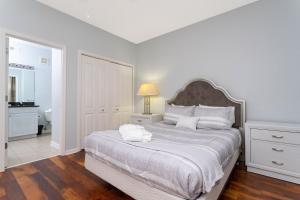 a white bedroom with a large bed and a bathroom at COZY Condo - Perfect Location Close to Disney in Kissimmee