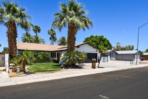 a house with palm trees on the side of the street at Yuma Vacation Rental with Private Pool and Patio! in Yuma