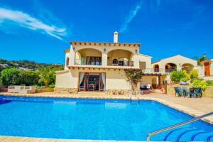 eine Villa mit einem Swimmingpool vor einem Haus in der Unterkunft Alice - holiday home with private swimming pool in Benissa in Benissa