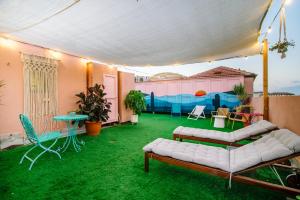 a patio with green grass and a couch and chairs at Pink & Blondie - Smart Hotel by Loginn Tel Aviv in Tel Aviv