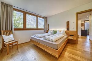 1 dormitorio con 1 cama grande y 1 silla en Pröfinghof - Urlaub auf dem Biobauernhof, en Parcines