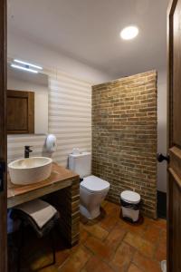 a bathroom with a sink and a toilet and a brick wall at Horta da Quinta in Mértola