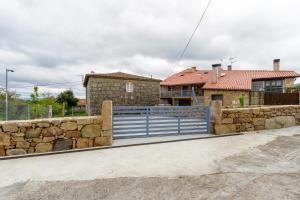 ein Haus mit einem blauen Zaun und einer Steinmauer in der Unterkunft Alojamiento Turístico Caxide Parada de Sil Ribeira Sacra in Parada de Sil