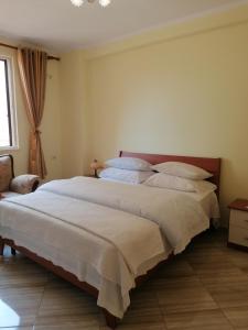 a bedroom with a large bed with white sheets at Holiday Center Apartment in Shkodër