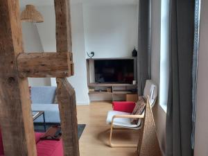 uma sala de estar com um sofá e uma televisão em Le Léon em Honfleur