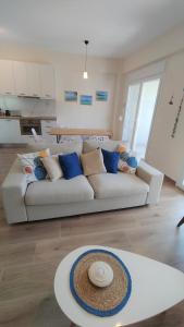 a living room with a white couch with blue pillows at To Helidoni Apartment & Gardens in Nikiti