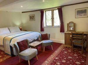 een slaapkamer met een bed en 2 stoelen en een bureau bij Gilberts End Farm in Great Malvern