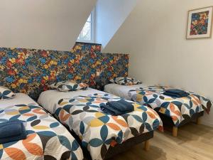 a room with two twin beds with colorful covers at Les prunelles maison de village de 4 à 8 personnes in Précigné