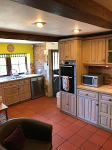 a large kitchen with wooden cabinets and appliances at Converted Coach House Holt, Wiltshire in Holt