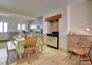 een keuken met een tafel en stoelen en een keuken met witte kasten bij River Cottage in Lynmouth