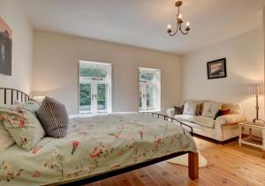 een slaapkamer met een bed, een bank en ramen bij River Cottage in Lynmouth