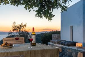 una bottiglia di vino seduta su un tavolo con due bicchieri di Casatino Villas a Kalianaíika
