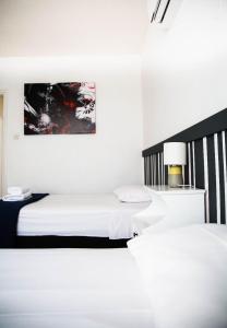um quarto branco com 2 camas e um candeeiro em Olive Island em Lárnaca