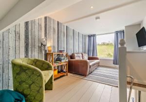 a living room with a couch and a chair at The Beach House - Porthcurno in Saint Levan