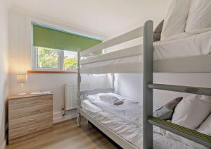 a bedroom with two bunk beds and a window at The Beach House - Porthcurno in Saint Levan