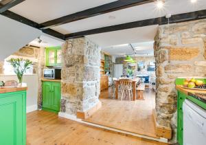 a kitchen with green cabinets and a stone wall at Boslandew House in Paul