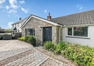 a stone house with a black door and a driveway at The Beach House - Porthcurno in Saint Levan