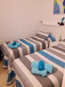 - 3 lits dans une chambre avec des serviettes bleues dans l'établissement Roda Golf gelijkvloers appartement, à Roda