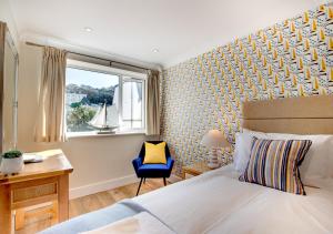 a bedroom with a bed and a chair and a window at Sea Spray in Westward Ho