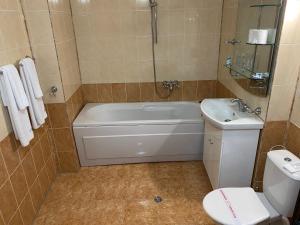 a bathroom with a tub and a toilet and a sink at Hotel Kamenec in Kiten