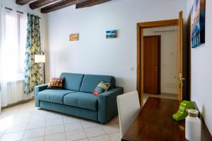 Una sala de estar con un sofá azul y una mesa. en Ca' Ormesini Lovely Apartment, en Venecia
