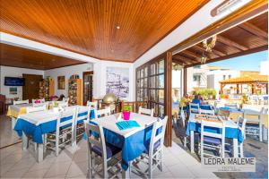 un restaurante con mesas blancas y sillas azules en Ledra Maleme Hotel, en Máleme